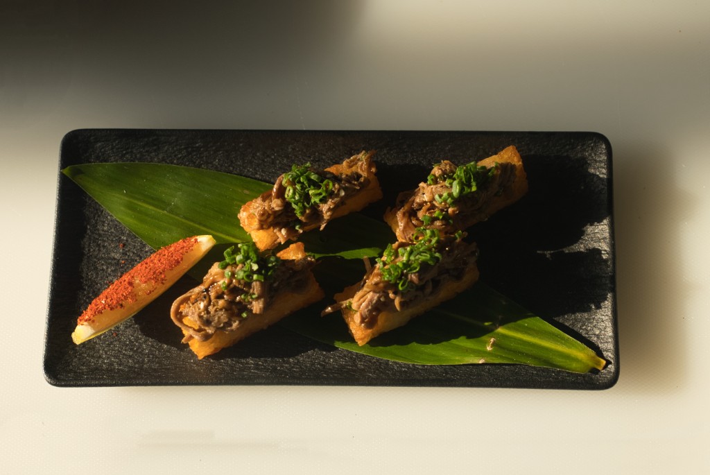 Four refined small plates on black slate with citrus and spice