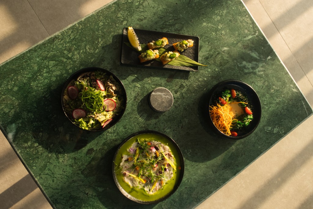 Chef’s table: four plated courses on green marble in golden-hour light